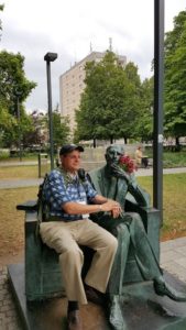 Image of Warsaw outside Polin Museum Irv sitting with statue tribute to Jan Karski, underground courier for the Polish government-in-exile, informed the West in the fall of 1942 about Nazi atrocities against Jews taking place in Poland.