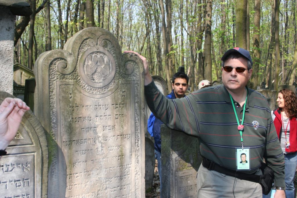 Image of Irv at Warsaw Cemetery headstones of his great grandparents.